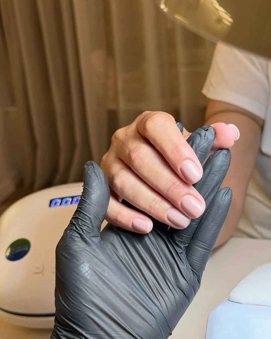 A technician finishing a soft nude gel manicure under the curing lamp at Urban Chic Beauty Lounge in Limassol